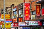 Stock photo of colorful street signs spanning several buildings on a street in the Chinatown section of the city of Toronto in Ontario, Canada.