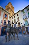 Stock photo of a statue of a Man and donkey in Plaza de la Romanilla with the bell tower of the Cathedral towering above, City of Granada, Province of Granada, Andalusia (Andalucia), Spain, Europe.