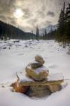 Stock photo of a stone cairn on the banks of the Mistaya River during winter after fresh snowfall with Mount Sarbach in the background, Mistaya Canyon, Icefields Parkway, Banff National Park, Canadian Rocky Mountains, Alberta, Canada.