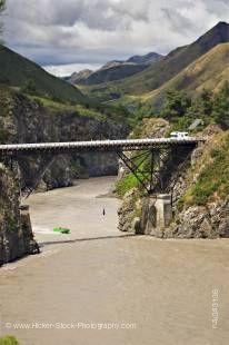 A jet boat speeds to pick up a Bungee Jumper shown hanging from the Waiau Ferry Bridge over the Waiau River and Thrill Seekers Canyon near Hanmer Springs, South Island, New Zealand.