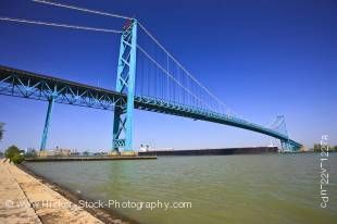 Stock photo of large bulk carrier ship passing under Ambassador Bridge expanding the Detroit River from Windsor, Ontario Canada to Detroit, Michigan, United States