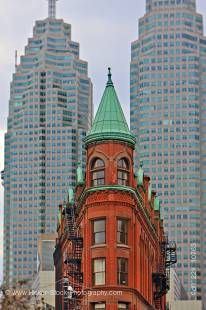 Stock photo of the red and green Gooderham building in front of two skyscarpers in downtown Toronto, Ontario, Canada.