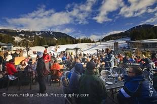 Hundreds of patrons seen seated outside the Longhorn Saloon and Grill, an apres-ski bar at the base of Whistler Mountain, Whistler Village, British Columbia, Canada. People dressed in their warm winter clothing enjoy food and drink at tables outside this 