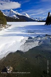 Srock photo of a partially frozen Maligne River in Winter as it drains from Maligne Lake, with a view of Leah and Samson Peaks along Maligne Lake Road in Jasper National Park in the Canadian Rocky Mountains in Alberta, Canada.