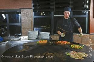 Stockphoto of a chef performing with utensils while preparing meals at the Mongolie Grill World Famous Stirfry Restaurant in Whistler Village, British Columbia, Canada. 