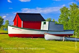 Stock photo shows two old boats and a bright red shed in Hecla Village on the shores of Lake Winnipeg, Hecla Island, Manitoba, Canada.