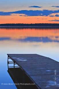 Stock photo of a wooden wharf extending onto Lake Audy looking out to the golden reflection of the magnificent sunset at Lake Audy, Riding Mountain National Park, Manitoba, Canada.